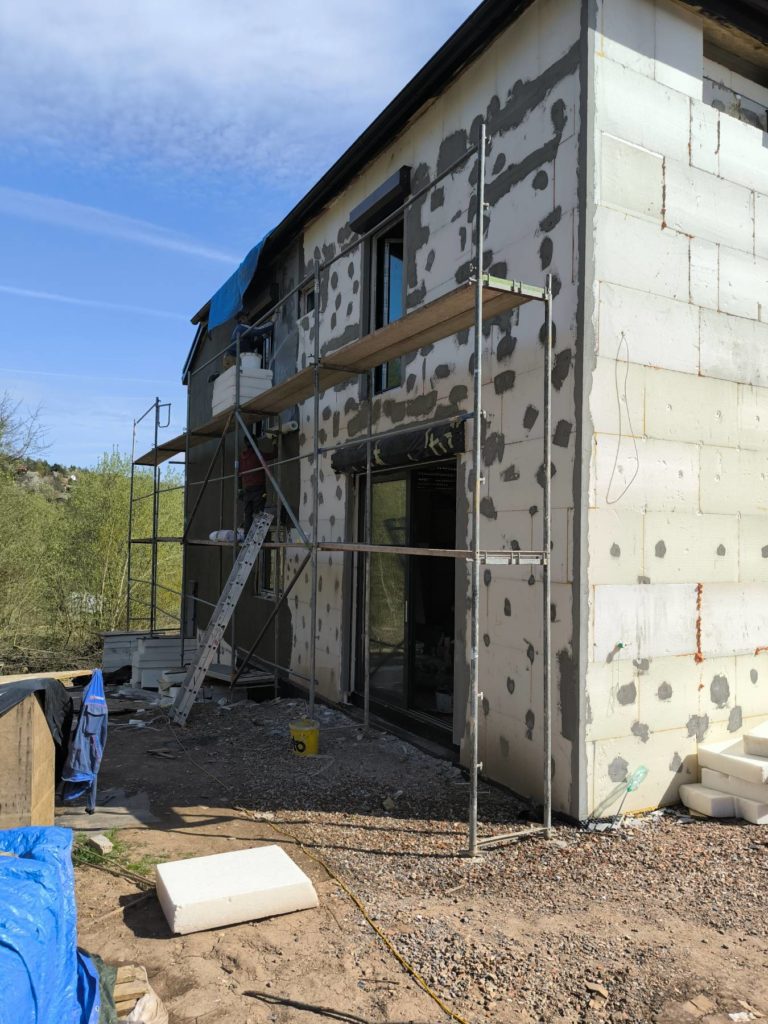 Montáž perlinky na polystyrenové zateplení na stavbě domu.
